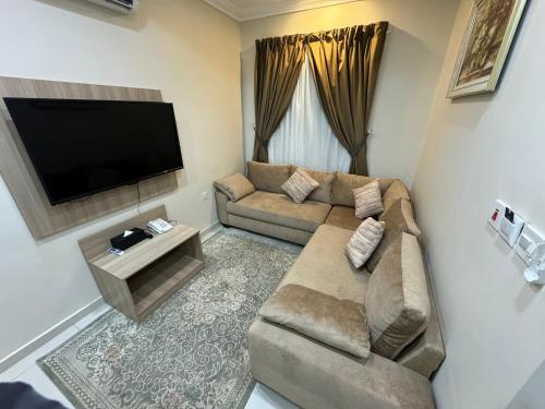 a living room with a couch and a flat screen tv at PRIMOTEL Suites As Salamah in Jeddah