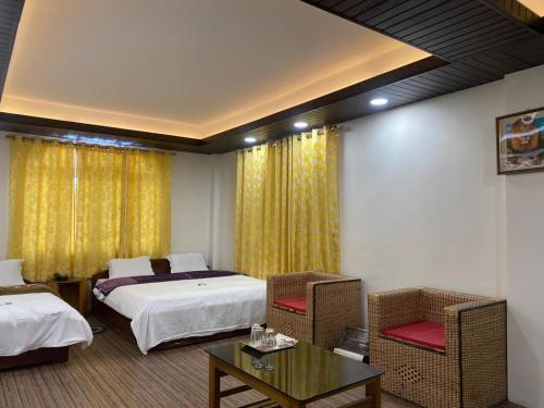 a hotel room with two beds and a table at Yul Pemakhar in Tawang