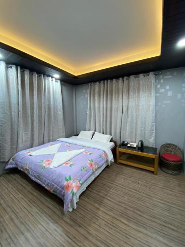 a bedroom with a bed with a purple comforter at Yul Pemakhar in Tawang