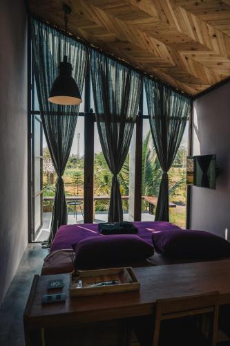 a bedroom with a bed with a table and a window at STAY PILAFarm in Ban Nam Chun Yai