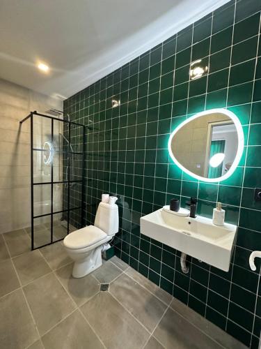 Baño de azulejos verdes con aseo y lavamanos en Green Villa Tsaghveri, en Tsaghveri