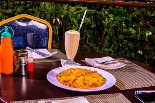a table with a plate of food and a drink at QUINTEN HOTEL KISUMU in Kisumu