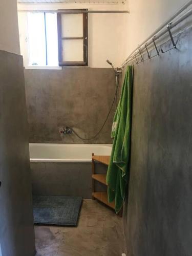 La salle de bains est pourvue d'une baignoire et d'une serviette verte. dans l'établissement La Bergerie en Cévennes, à Mialet