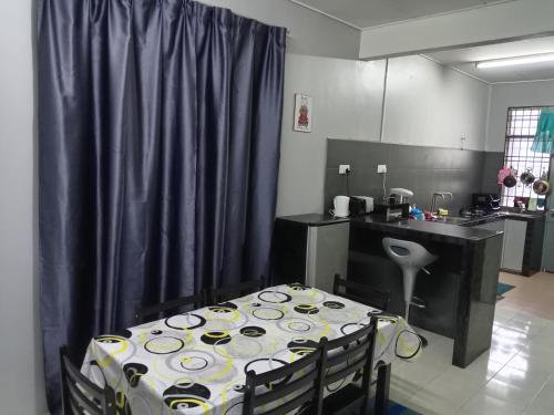 a room with a table and a kitchen with purple curtains at RizqFateh Homestay in Kluang
