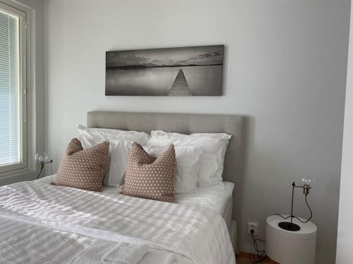 een slaapkamer met een bed met witte lakens en kussens bij Beautiful apartment - own parking space included in Vantaa