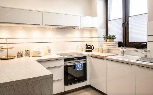 a kitchen with white cabinets and a stove top oven at APARTAMENTY NOWE CENTRUM 2 in Łódź