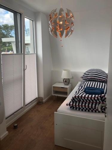 um quarto branco com uma cama e um lustre em Schwimmendes Ferienhaus Heimathafen em Großenbrode