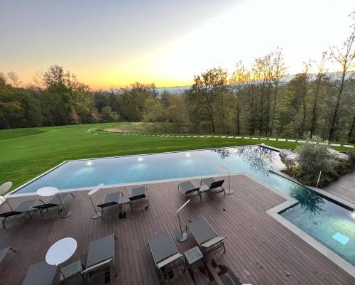 a swimming pool with tables and chairs next to a field at Le Cattedrali Relais by Laqua Collection in Asti