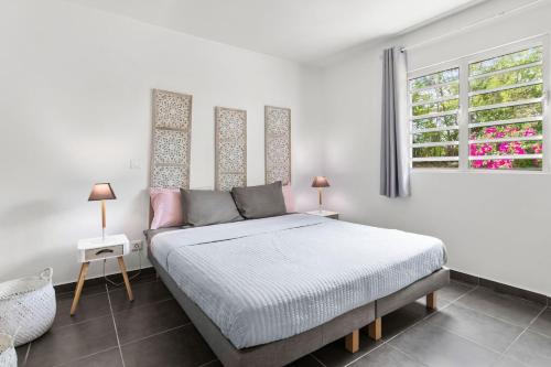 a white bedroom with a bed and a window at Le Cosmopolitain_ Appart 4/5p terrasse piscine in Cul de Sac