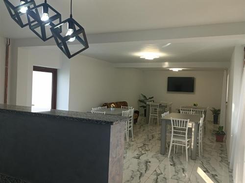 a dining room with a bar with chairs and a tv at Pensiunea Ileana in Novaci