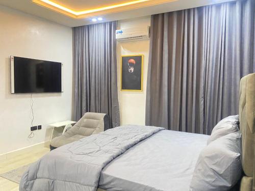 a bedroom with a bed and a chair and a flat screen tv at MAJESTIC VILLA RESIDENCE in Ankuru