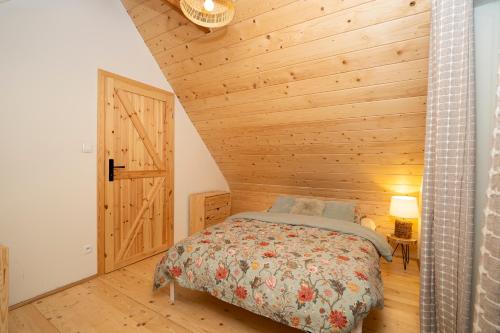 1 dormitorio con 1 cama y pared de madera en Poleskie zacisze, domek na wyłączność , Wi - fi, Domek Czapla 