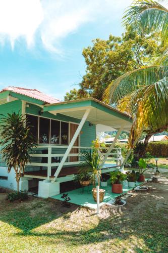 a green house with palm trees in front of it at Pangkor Sandy Beach Resort in Pangkor
