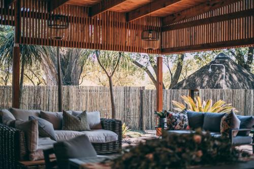 an outdoor patio with couches and a fence at Tshikwalo Game Lodge in Klipdrift
