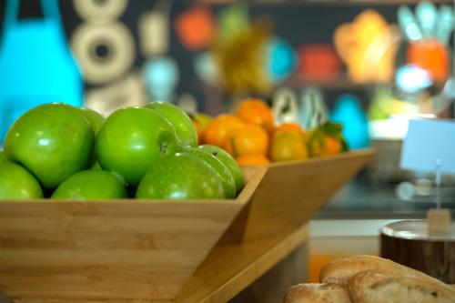 a wooden bowl of apples and oranges on a table at ibis Styles Lyon Sud Vienne in Chasse-sur-Rhône