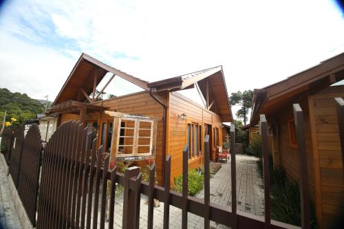 a wooden house with a fence in front of it at Pousada Vila dos Butias in Urubici