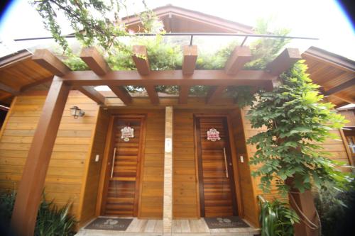 a wooden house with a pergola over the doors at Pousada Vila dos Butias in Urubici