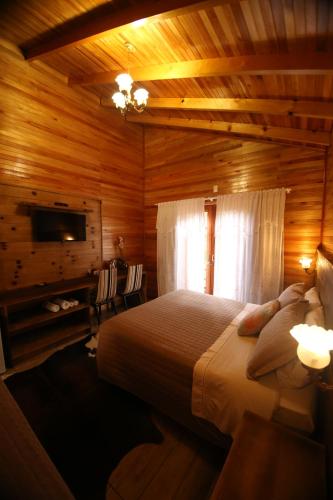 a bedroom with a large bed in a wooden room at Pousada Vila dos Butias in Urubici
