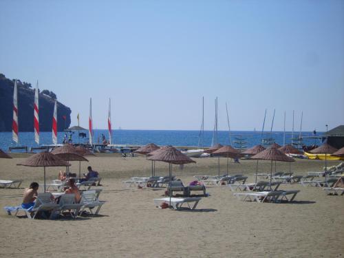 a group of people sitting on a beach with umbrellas at Villa Rana The Royal Links Sarigerme in Ortaca
