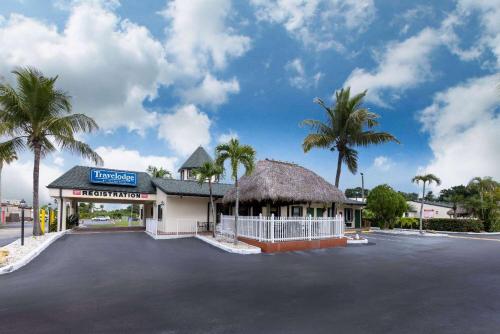 a parking lot in front of a building with palm trees at Travelodge by Wyndham Florida City/Homestead/Everglades in Florida City