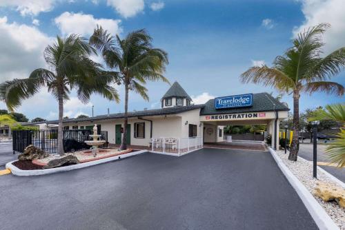 un bâtiment avec des palmiers dans le parking dans l'établissement Travelodge by Wyndham Florida City/Homestead/Everglades, à Florida City