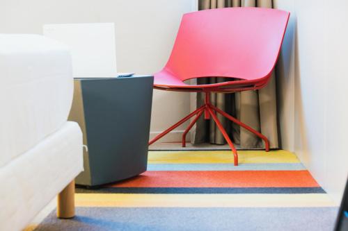 a pink chair sitting on a colorful rug in a room at ibis Styles Lyon Sud Vienne in Chasse-sur-Rhône
