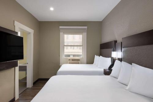 a hotel room with two beds and a flat screen tv at Super 8 by Wyndham San Francisco/Union Square Area in San Francisco