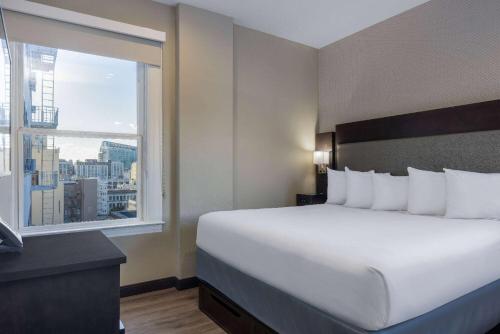 a hotel room with a large bed and a window at Super 8 by Wyndham San Francisco/Union Square Area in San Francisco