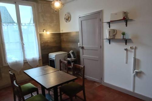 a dining room with a table and a table and a door at Appartement rez de jardin in La Chartre-sur-le-Loir