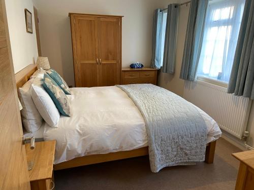 1 dormitorio con 1 cama blanca y armario de madera en The Bothy en Lyndhurst