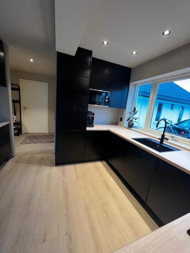 a kitchen with black cabinets and a sink and a window at Nytt hus i rolig familiestrøk in Verdal