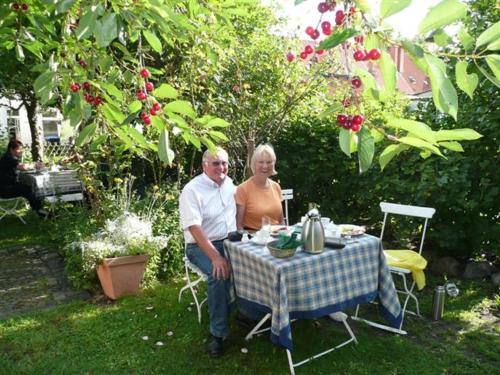 a man and woman sitting at a table in a garden at Hotel Reingard in Wismar