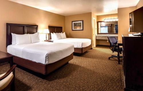 フォーチュナにあるBest Western Country Innのベッド2台とデスクが備わるホテルルームです。