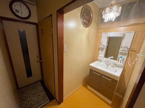 a bathroom with a sink and a clock on the wall at AnNam Stay TOYONAKA in Toyonaka