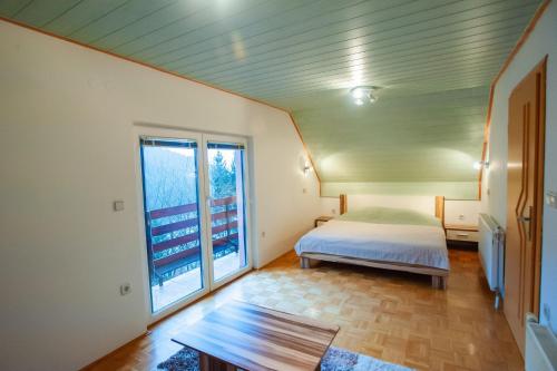 Country House & Spa في Mislinja: غرفة نوم بسرير ونافذة كبيرة