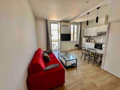 sala de estar con sofá rojo y cocina en Agréable deux pièces spacieux / climatisé / balcon, en Niza