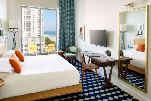 a hotel room with a bed and a desk and a mirror at The Confidante Miami Beach, part of Hyatt in Miami Beach