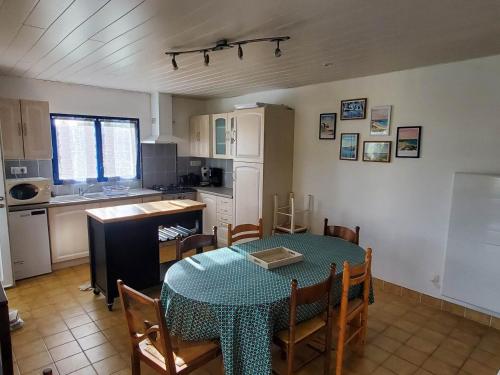 une cuisine avec une table et des chaises ainsi qu'une cuisine avec une table dans l'établissement Au calme, à 250 mètres de la plage et des dunes, à Ploudalmézeau