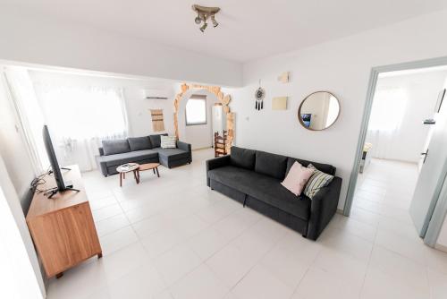 a living room with two black couches and a tv at 2 bed, Kapparis, Trinidad - 2A in Paralimni
