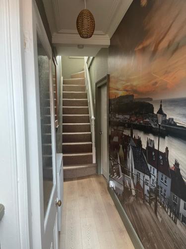a hallway with stairs and a painting on the wall at Snuze Whitby in Whitby