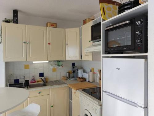 une cuisine avec des armoires blanches et un réfrigérateur blanc dans l'établissement appartement Cosy les pieds dans le sable, au Barcarès