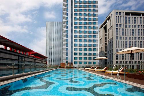 a large swimming pool on top of a building with tall buildings at Humble House Taipei, Curio Collection by Hilton in Taipei