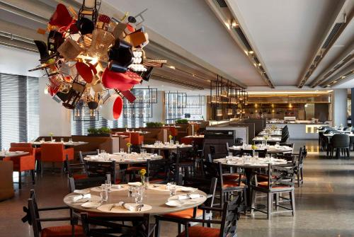 a restaurant with white tables and chairs and a chandelier at Humble House Taipei, Curio Collection by Hilton in Taipei