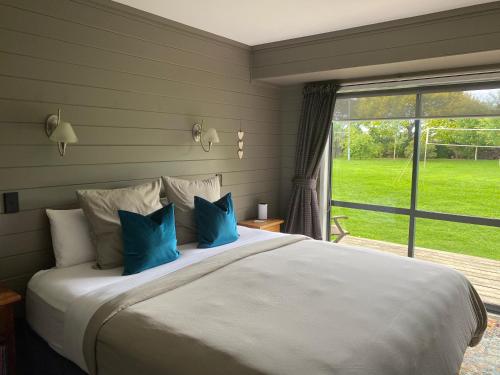 a bedroom with a large bed with blue pillows and a window at Garden Oasis in the heart of Pāpāmoa in Tauranga