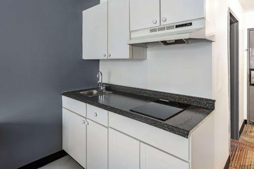 uma cozinha com armários brancos e um lavatório em Quality Inn & Suites em Caribou
