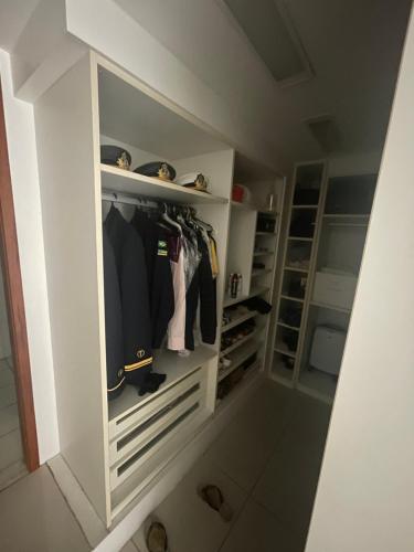 um closet com armários brancos e roupas em Luxuoso loft no circuito do carnaval em Salvador