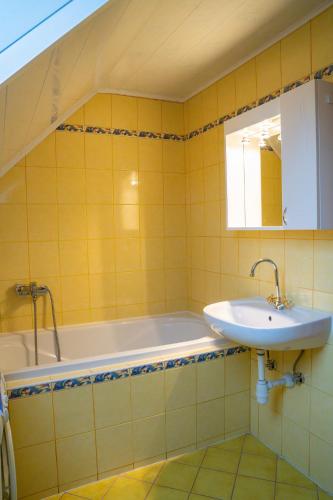 a yellow tiled bathroom with a sink and a tub at Country House & Spa in Mislinja