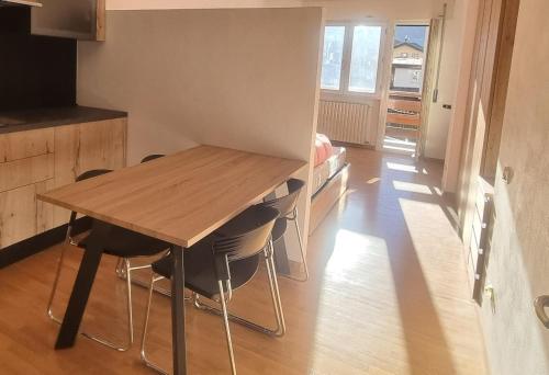 uma cozinha com uma mesa de madeira e algumas cadeiras em Studio Apartment Ariston in centro a Cortina em Cortina dʼAmpezzo