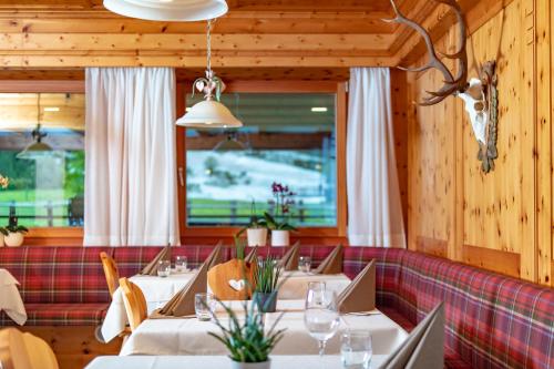 um restaurante com mesas brancas e um sofá vermelho em Pederü em San Vigilio Di Marebbe