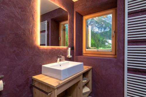 een badkamer met een witte wastafel en een spiegel bij Pederü in San Vigilio Di Marebbe